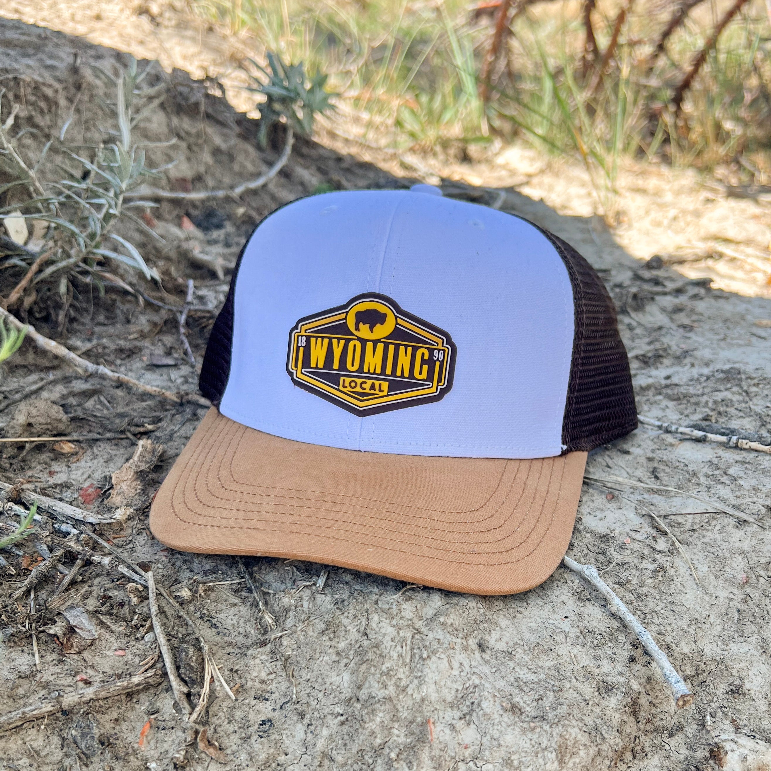 Brown and Gold Wyoming PVC Patch Hat. Hat structure is white front, brown mesh, gold bill. Roam Around Wear is a Wyoming company printed in Wright, W